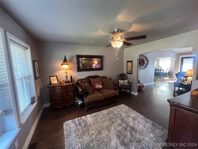 living room with ceiling fan, a textured ceiling, and dark hardwood / wood-style flooring