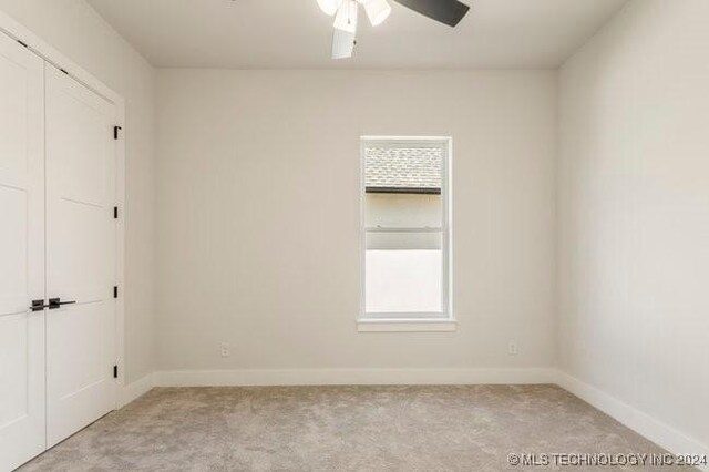 carpeted spare room with ceiling fan and plenty of natural light