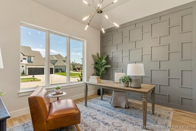 office with light hardwood / wood-style floors and an inviting chandelier