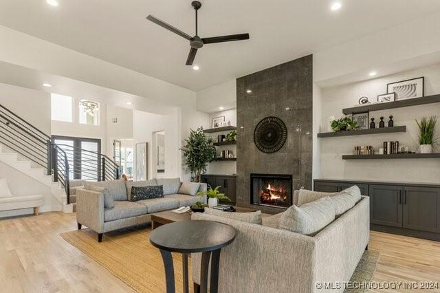 living room featuring light hardwood / wood-style floors, a large fireplace, and ceiling fan