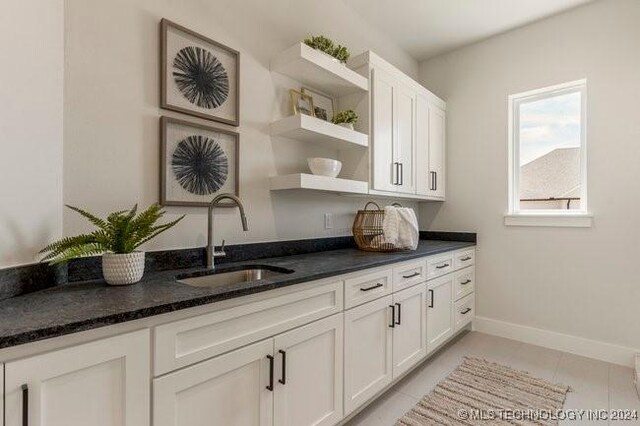 interior space featuring sink, white cabinets, dark stone countertops, and light tile patterned floors