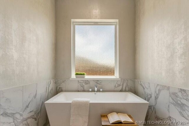 bathroom featuring tile walls and a bathing tub