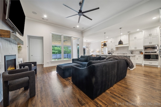 living room featuring sink, crown molding, dark hardwood / wood-style floors, and ceiling fan with notable chandelier