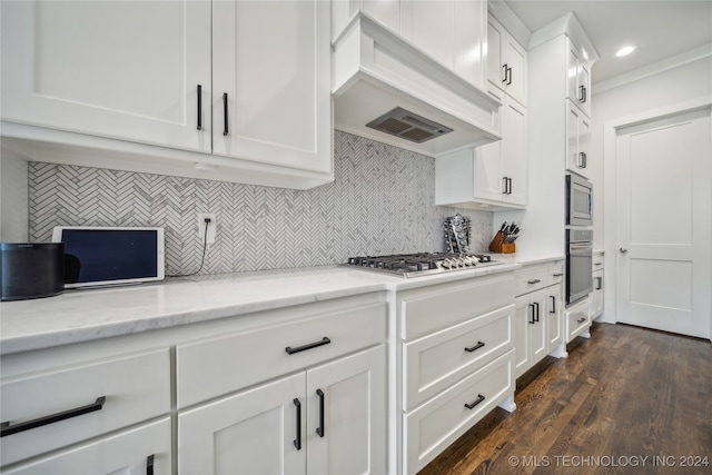 kitchen with dark hardwood / wood-style floors, light stone countertops, white cabinetry, custom exhaust hood, and appliances with stainless steel finishes