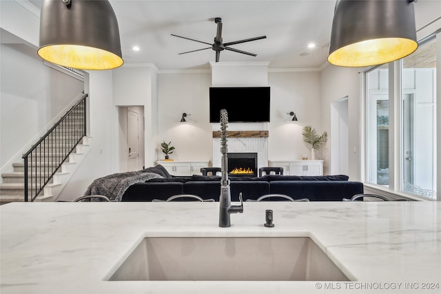 kitchen with ornamental molding, light stone counters, and ceiling fan