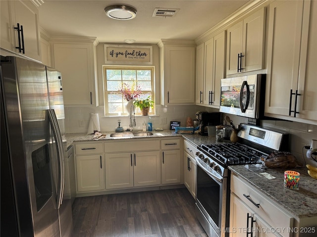 kitchen featuring light stone countertops, dark wood-type flooring, appliances with stainless steel finishes, and sink