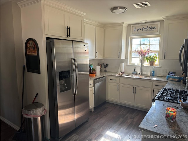 kitchen with sink, appliances with stainless steel finishes, white cabinets, light stone countertops, and dark wood-type flooring