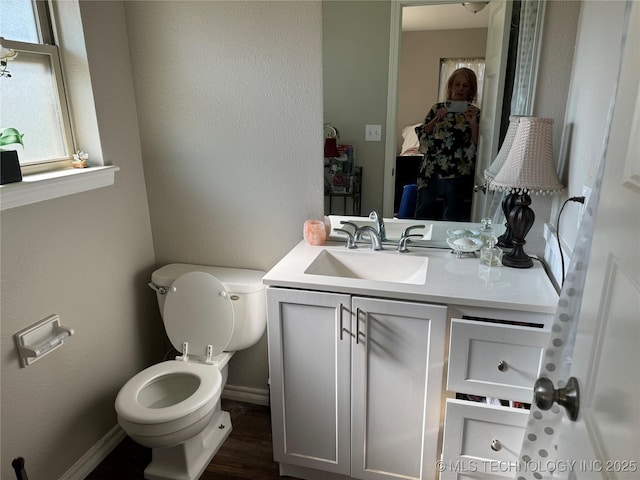 bathroom with toilet, vanity, and hardwood / wood-style floors