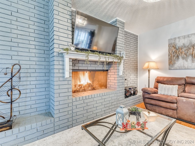 living room featuring a fireplace, a textured ceiling, and brick wall