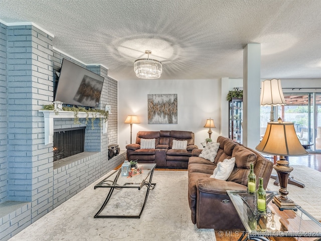 living room featuring an inviting chandelier, brick wall, a textured ceiling, and a brick fireplace