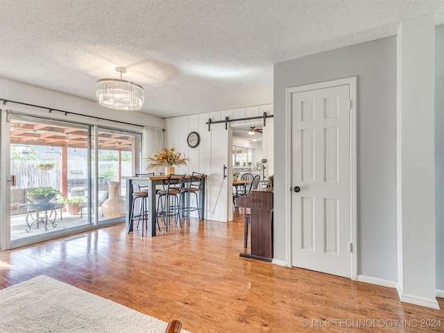 dining space featuring wood-type flooring, ceiling fan with notable chandelier, a textured ceiling, and a wealth of natural light