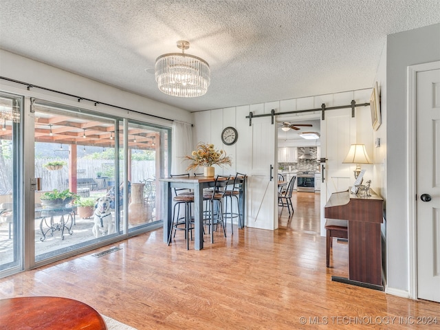 dining area featuring ceiling fan with notable chandelier, a textured ceiling, and light hardwood / wood-style flooring