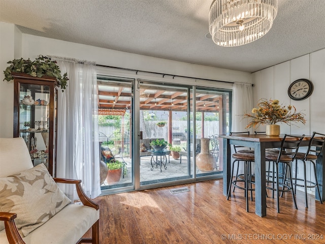 dining room with wood-type flooring, a textured ceiling, and an inviting chandelier