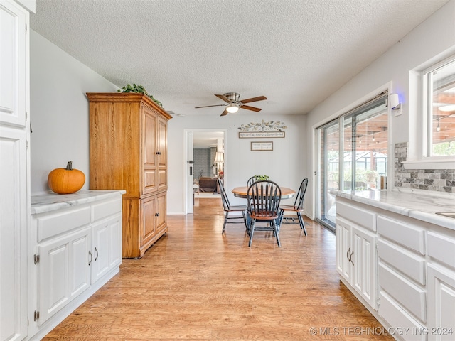 dining space with ceiling fan, a textured ceiling, and light wood-type flooring