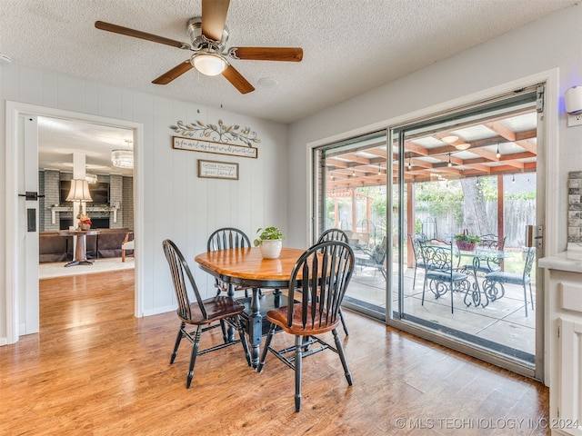 dining area featuring a textured ceiling, light wood-type flooring, ceiling fan, and a healthy amount of sunlight