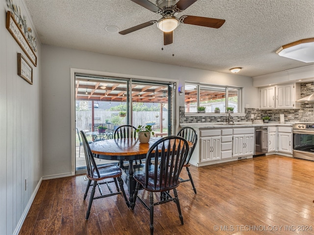 dining room with a textured ceiling, light wood-type flooring, ceiling fan, and wooden walls