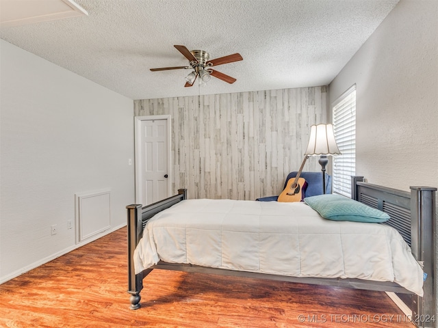 bedroom featuring ceiling fan, wood-type flooring, and a textured ceiling