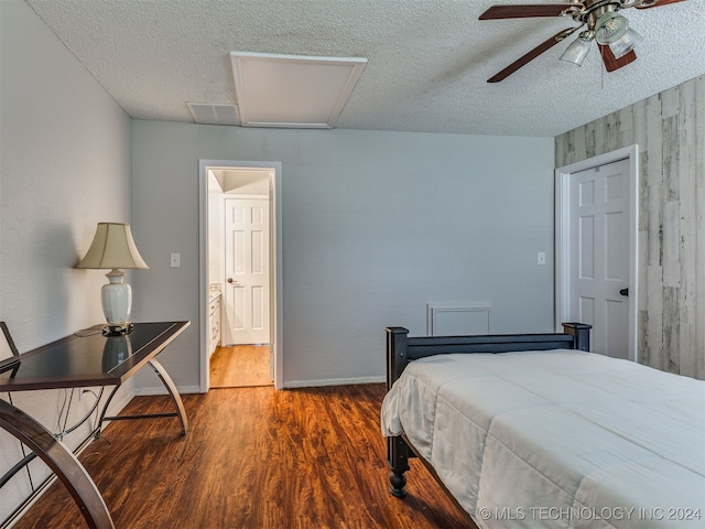 bedroom with ceiling fan, wood-type flooring, a textured ceiling, and wooden walls