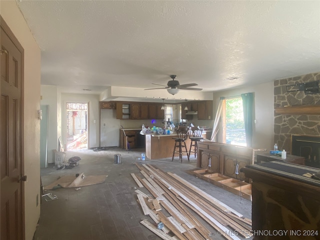 living room with a fireplace, a textured ceiling, dark hardwood / wood-style floors, and ceiling fan