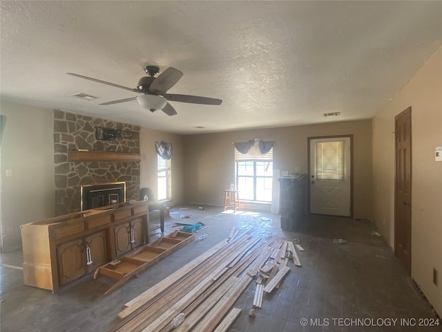 unfurnished living room featuring a textured ceiling, ceiling fan, a fireplace, and dark hardwood / wood-style flooring