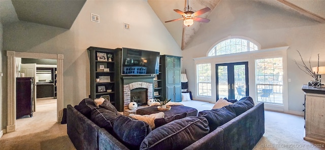 living room with ceiling fan, high vaulted ceiling, a stone fireplace, french doors, and light colored carpet