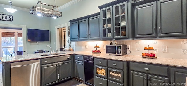 kitchen with appliances with stainless steel finishes, sink, kitchen peninsula, pendant lighting, and ornamental molding