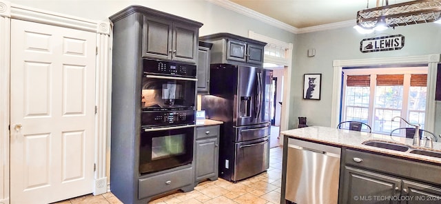 kitchen with hanging light fixtures, appliances with stainless steel finishes, sink, and ornamental molding