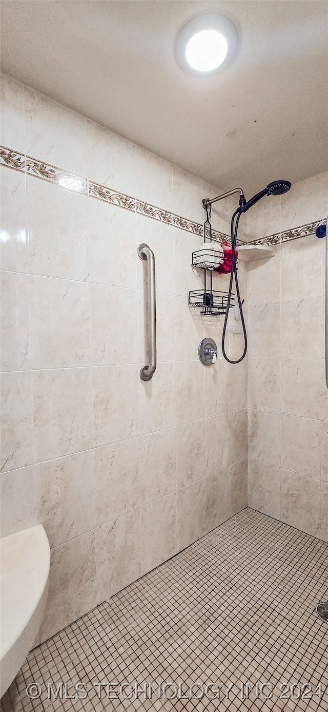 bathroom with a tile shower, toilet, and tile patterned flooring