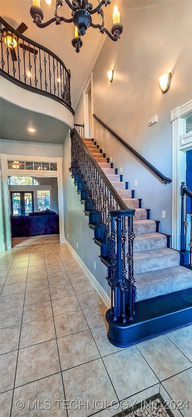 stairs with tile patterned floors and a towering ceiling