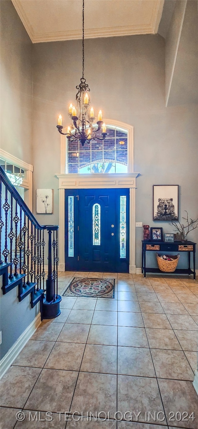 entryway featuring crown molding, tile patterned floors, and a towering ceiling