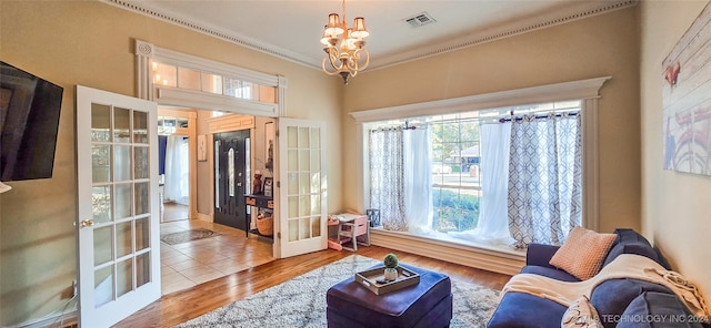 sitting room with french doors, light hardwood / wood-style flooring, a notable chandelier, and crown molding