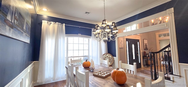 dining space featuring ornamental molding, hardwood / wood-style floors, and a notable chandelier