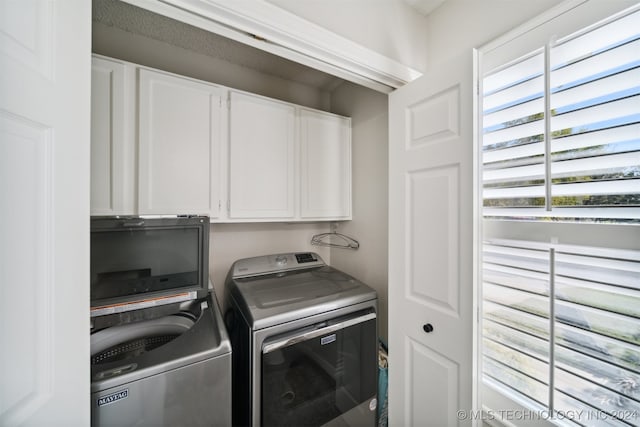 clothes washing area featuring washer and clothes dryer and cabinets