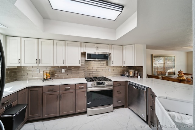 kitchen featuring decorative backsplash, white cabinets, stainless steel appliances, and light stone counters