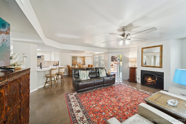 tiled living room with ceiling fan, crown molding, and sink