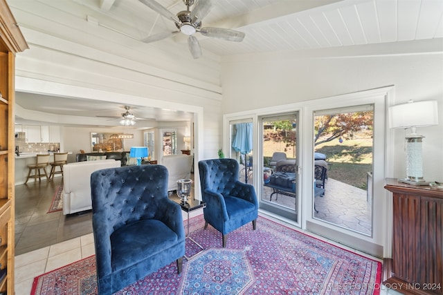 sitting room with ceiling fan, lofted ceiling with beams, and light tile patterned flooring