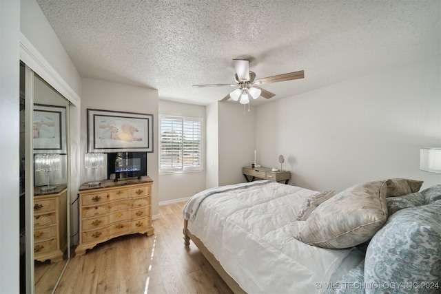 bedroom with ceiling fan, hardwood / wood-style flooring, and a textured ceiling