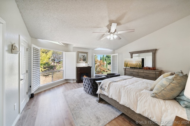 bedroom featuring vaulted ceiling, multiple windows, light wood-type flooring, and ceiling fan