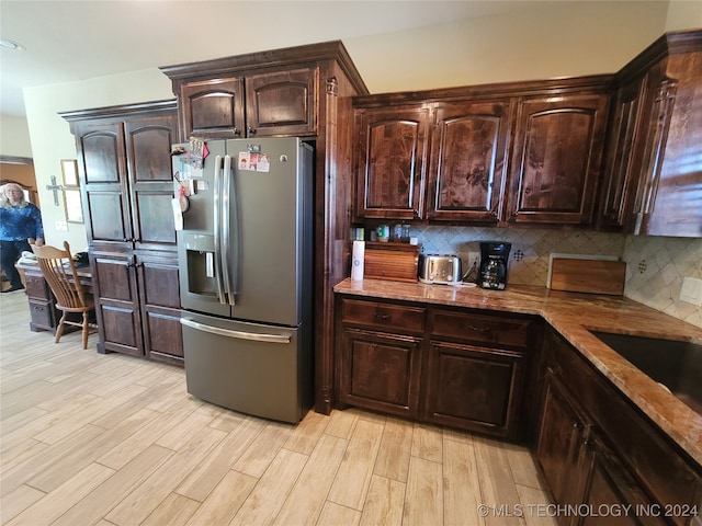 kitchen featuring sink, light wood-type flooring, dark brown cabinets, decorative backsplash, and stainless steel refrigerator with ice dispenser