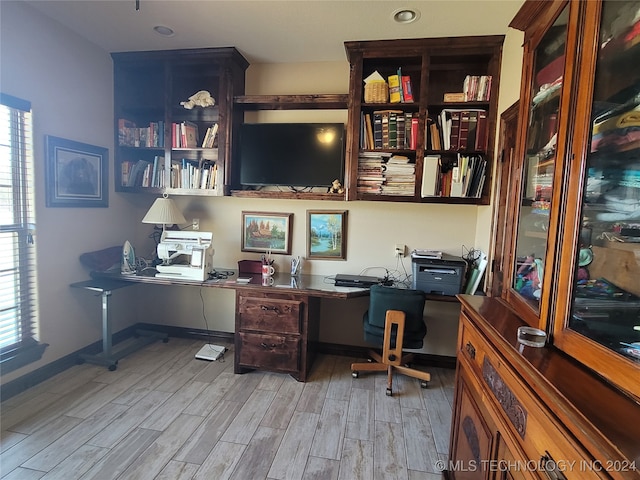 office space with built in desk and light wood-type flooring