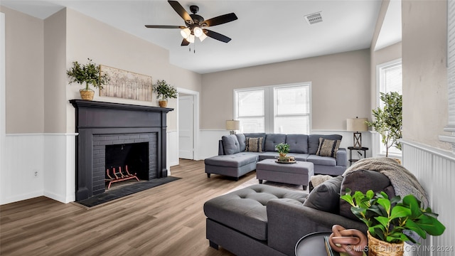 living room featuring hardwood / wood-style flooring, ceiling fan, plenty of natural light, and a brick fireplace