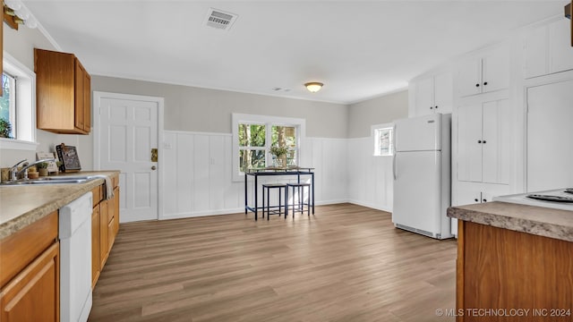 kitchen with white appliances, ornamental molding, sink, and light wood-type flooring