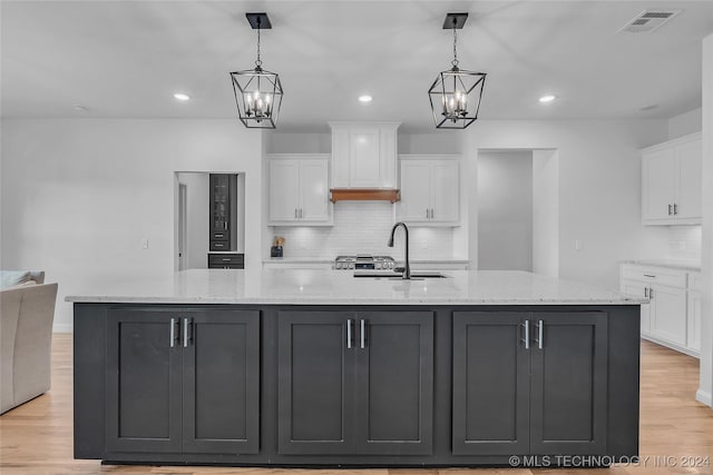 kitchen featuring hanging light fixtures, sink, white cabinets, and a spacious island