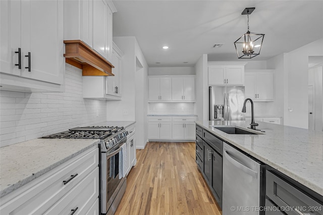 kitchen with white cabinetry, hanging light fixtures, stainless steel appliances, light hardwood / wood-style flooring, and a chandelier