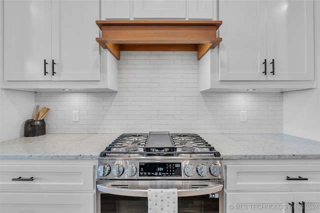 kitchen with gas stove, white cabinetry, custom range hood, and tasteful backsplash