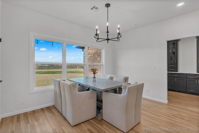 dining space with breakfast area, light hardwood / wood-style flooring, a wealth of natural light, and a notable chandelier