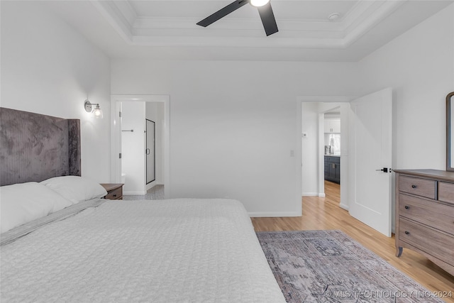 bedroom with ceiling fan, light hardwood / wood-style floors, ornamental molding, and a tray ceiling