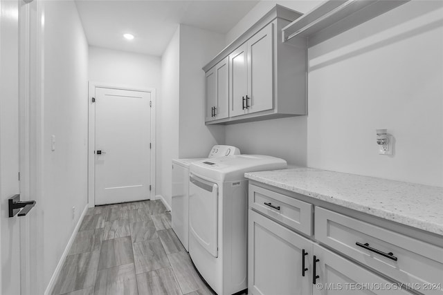 clothes washing area featuring cabinets and separate washer and dryer