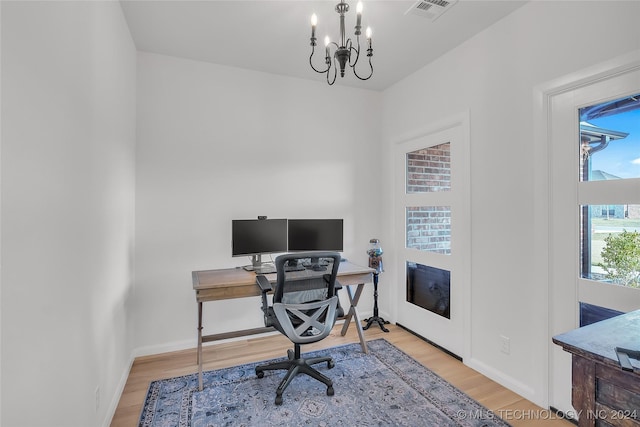 office area with light hardwood / wood-style floors and an inviting chandelier