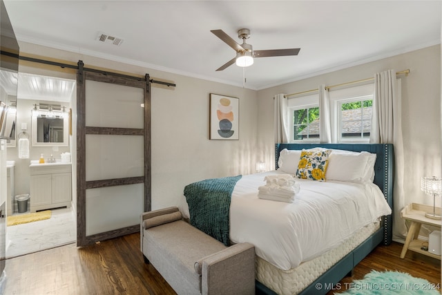 bedroom featuring dark hardwood / wood-style floors, ensuite bath, ornamental molding, a barn door, and ceiling fan